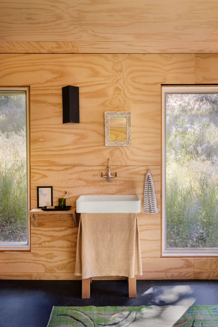 A neutral, upcycled fabric sink skirt in a minimalist, low-impact bathroom design.
