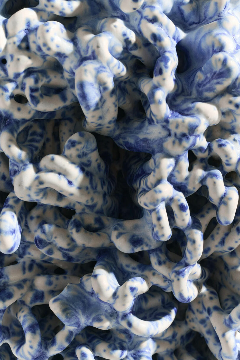 Abstract close-up of an intricate blue and white ceramic sculpture with organic, wave-like forms.