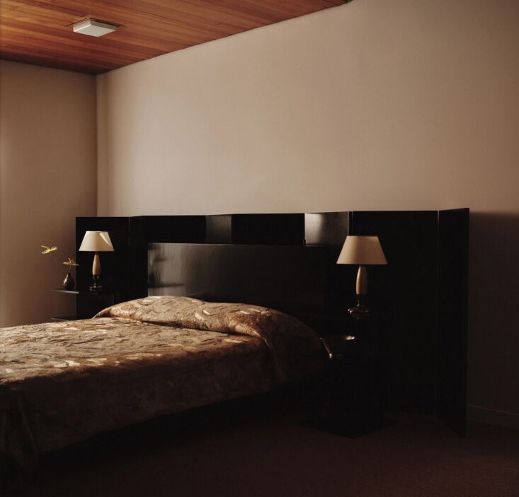 A black lacquered folding screen used as a headboard in a minimalist bedroom designed by Courtney Applebaum.
