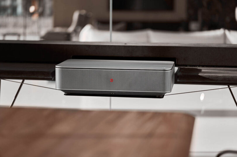 A close-up shot of the silver Leica Cine 1 projector unit on a minimalist shelf.