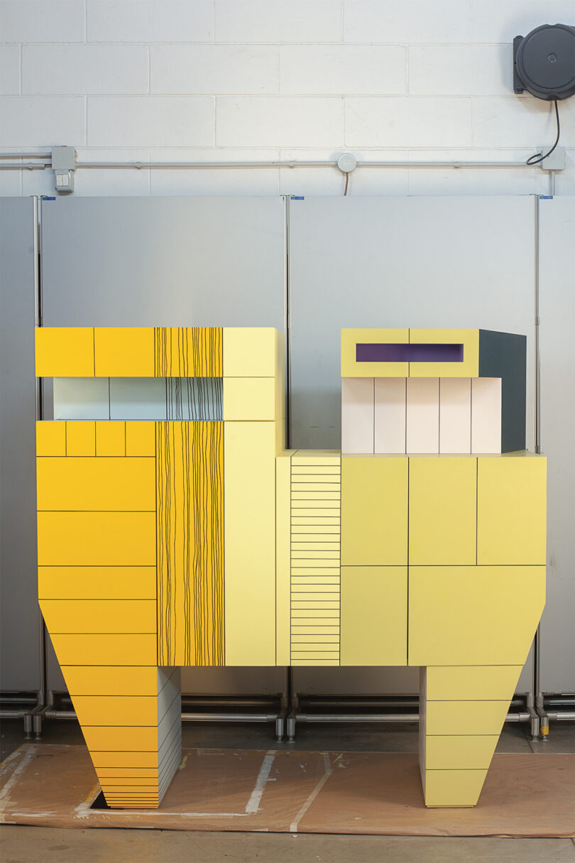 Detailed view of a yellow-toned geometric cabinet with vertical linear textures and unique handles.