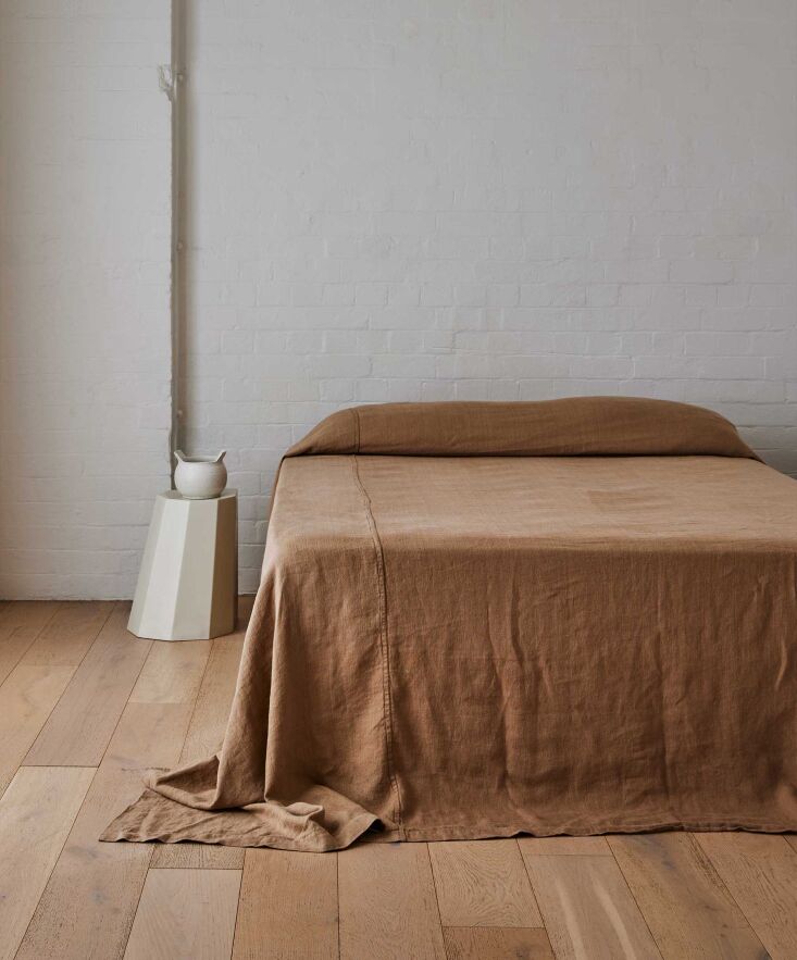 A close-up of a sand-colored heavyweight linen bedcover showing a thick, durable weave.