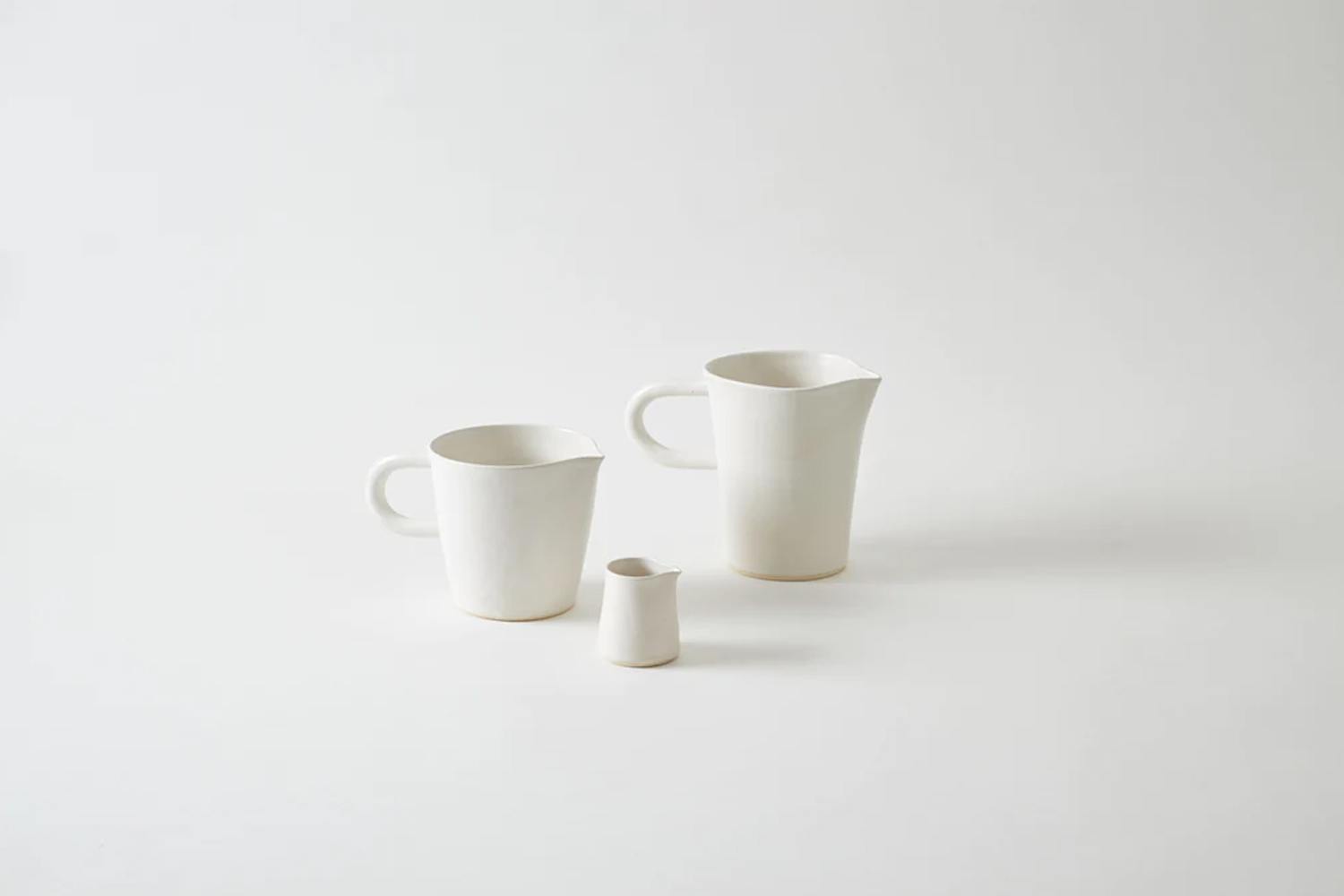 A handmade white ceramic pitcher with visible artisanal details.