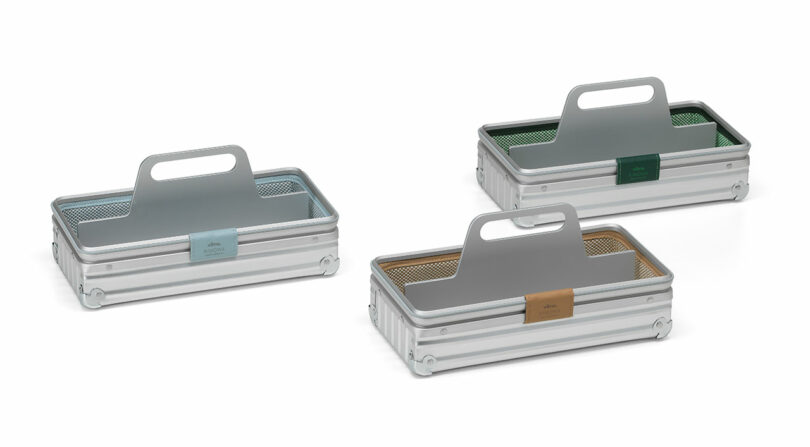 Three silver rectangular aluminum toolboxes with handles and mesh liners in blue, green, and tan.