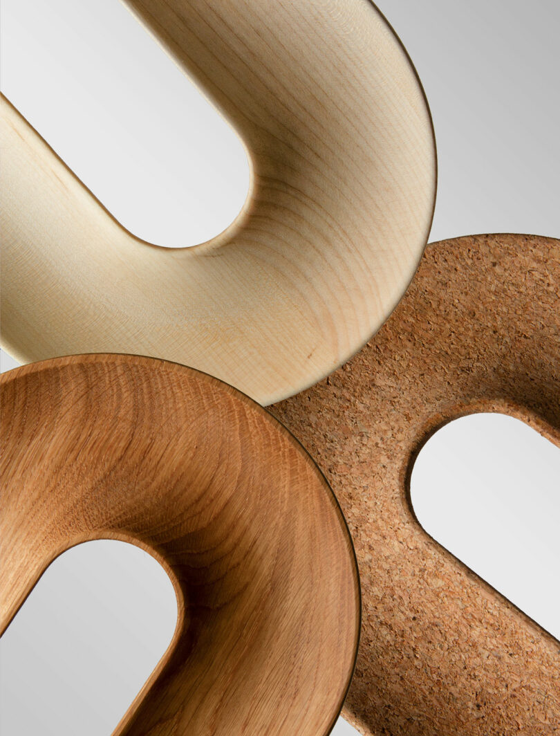 Three U-shaped wooden and cork objects overlapping to show different grains and textures.