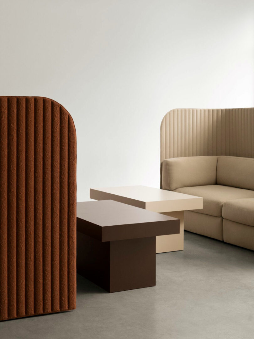 A neutral-toned modular sofa and textured brown room divider on a concrete floor.