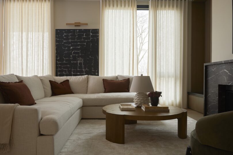 A cozy living room with a large beige sectional sofa and neutral curtains.