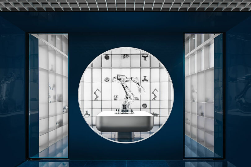 A robotic arm on display within a blue circular architectural window.