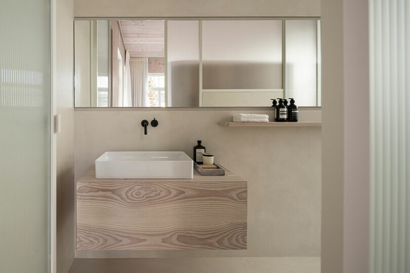 A minimalist bathroom with a light wood vanity and a clean, modern aesthetic.
