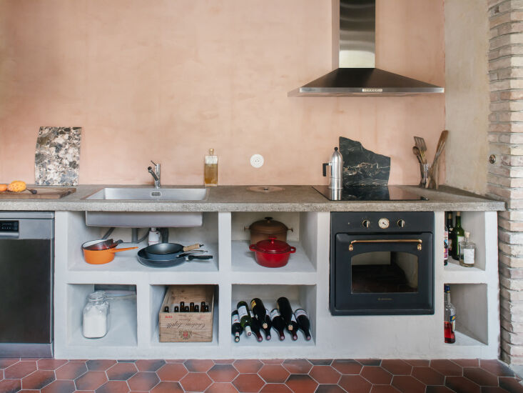 A minimalist kitchen area with plaster-coated aerated concrete and vintage 1970s floor tiles.