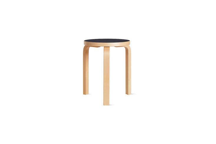 An Alvar Aalto Stool 60 with a black top used as a bedside table.