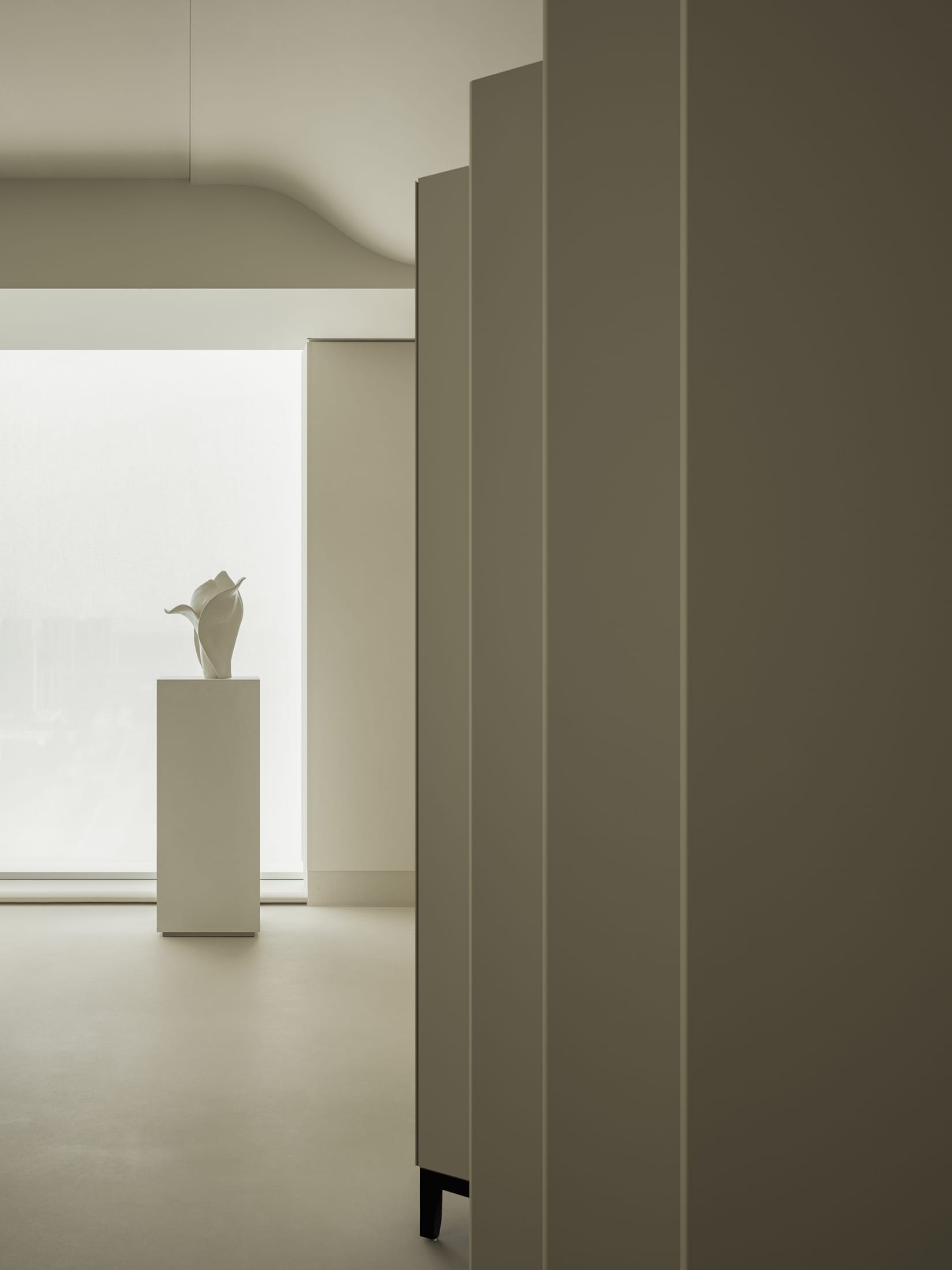 A view from one room looking through a square architectural frame into another sunlit space.