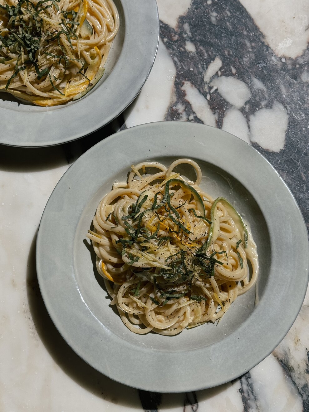 An aesthetic overhead view of a summer pasta dinner on a rustic table.