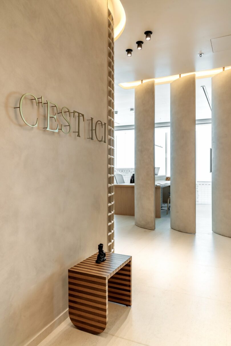 Curved beige partition walls leading into the main office area with C'est Ici branding.