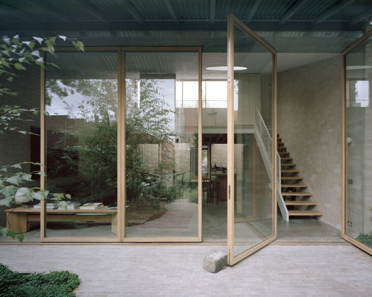 A row of towering 10.5-foot-tall glass pivot doors that open to a garden.