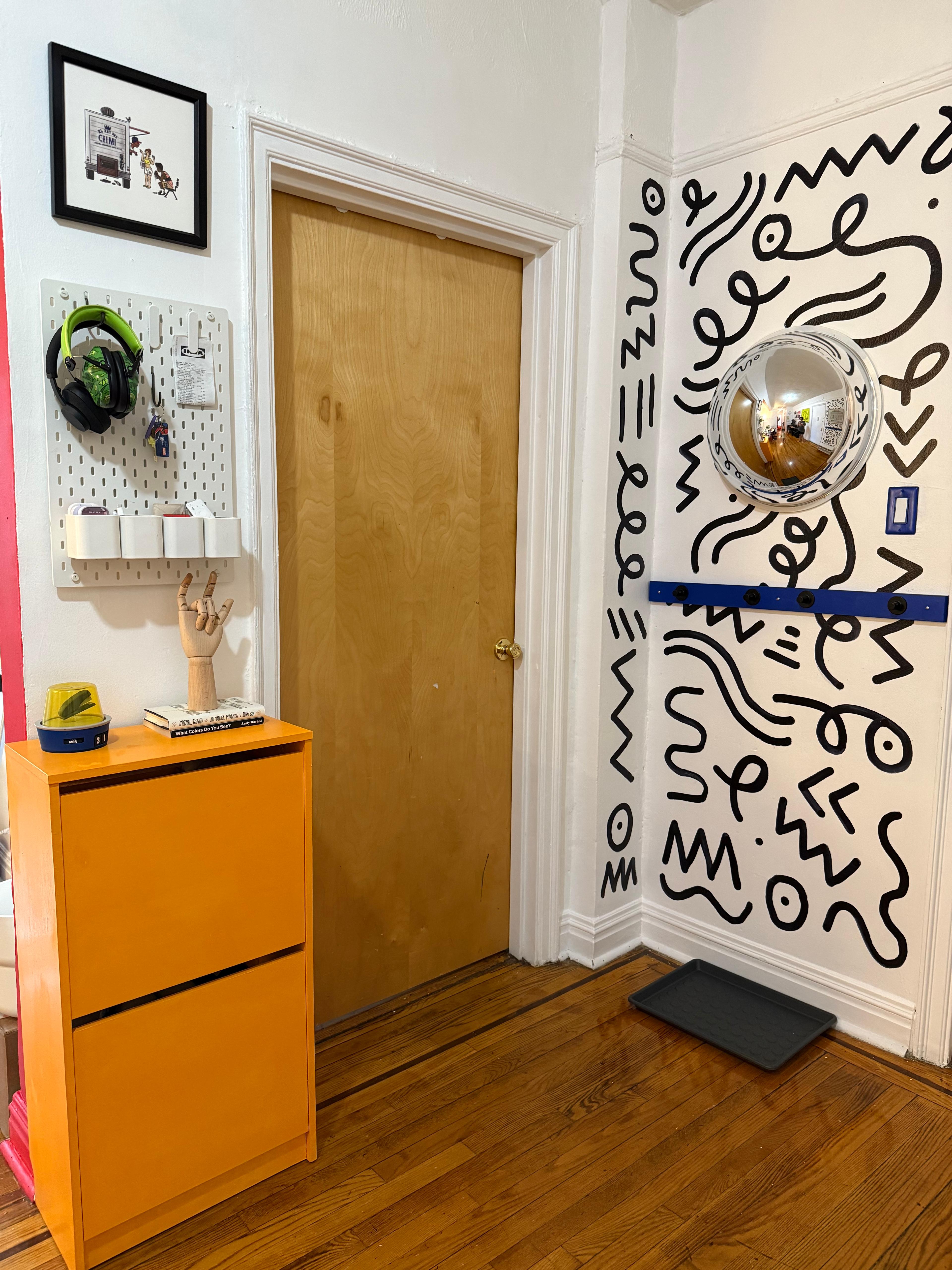 Close-up of low-mounted wooden hooks and a small drawer system at child height.