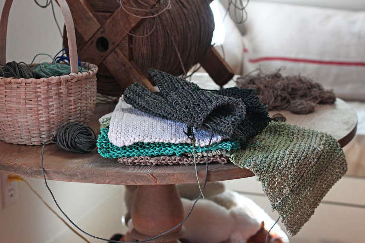 A stack of various hand-knit pot holders in shades of green, foam, and natural jute.
