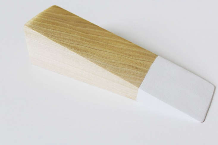 A wooden wedge with blue painter's tape and a freshly painted white tip.