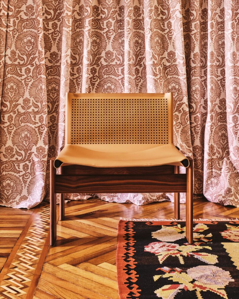 A Monk armchair on a parquet floor in a room with floral curtains and traditional decorative elements.