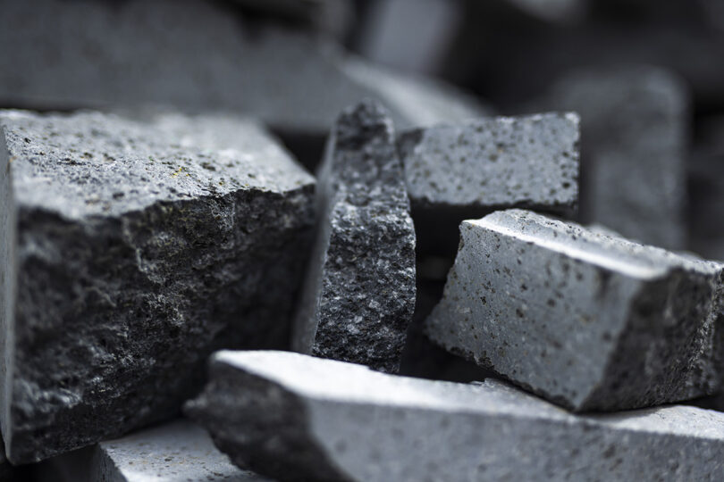 Close-up of stacked, raw grey volcanic stone blocks with rough, porous textures.