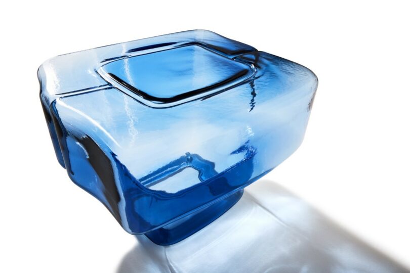 Close-up of a blue mouth-blown glass sculpture with rounded edges and translucent depth.