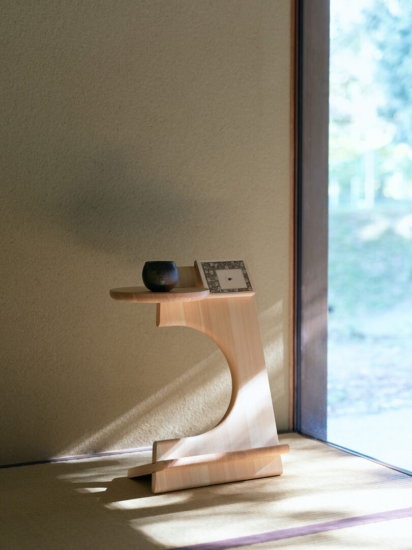 A sunlit wooden stand with a ceramic cup and a photo frame on a traditional tatami mat floor.