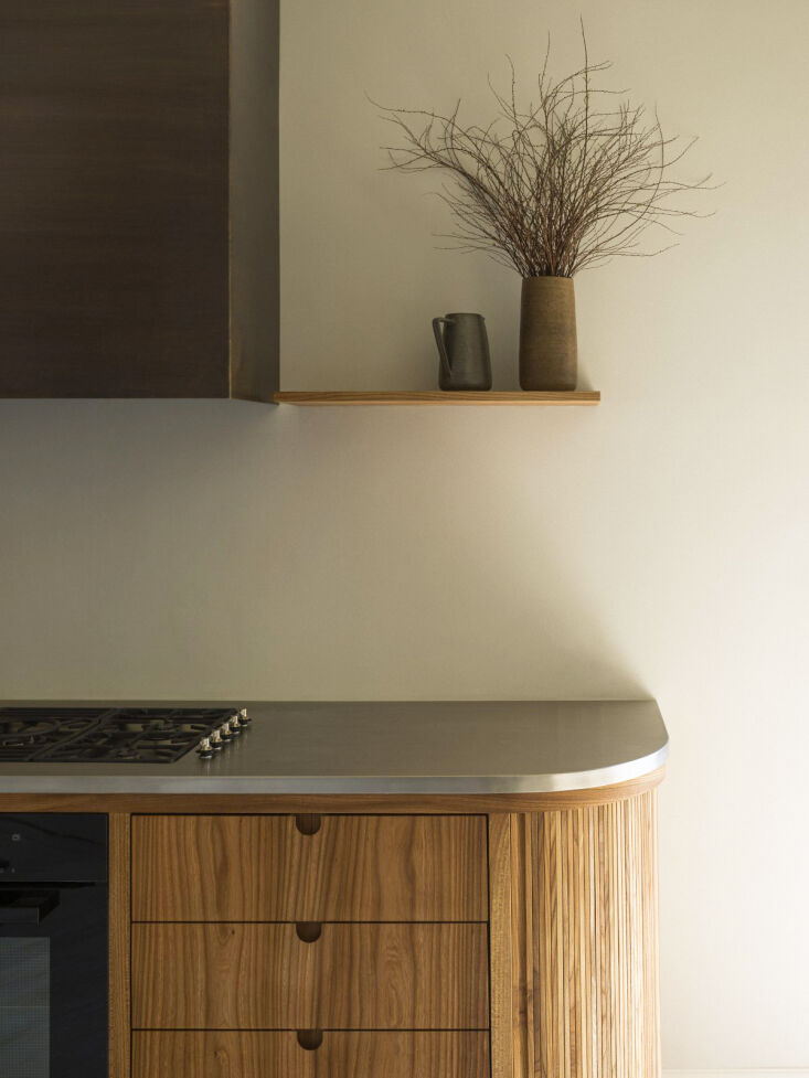 A sleek custom stainless steel kitchen worktop integrated with wooden cabinetry.
