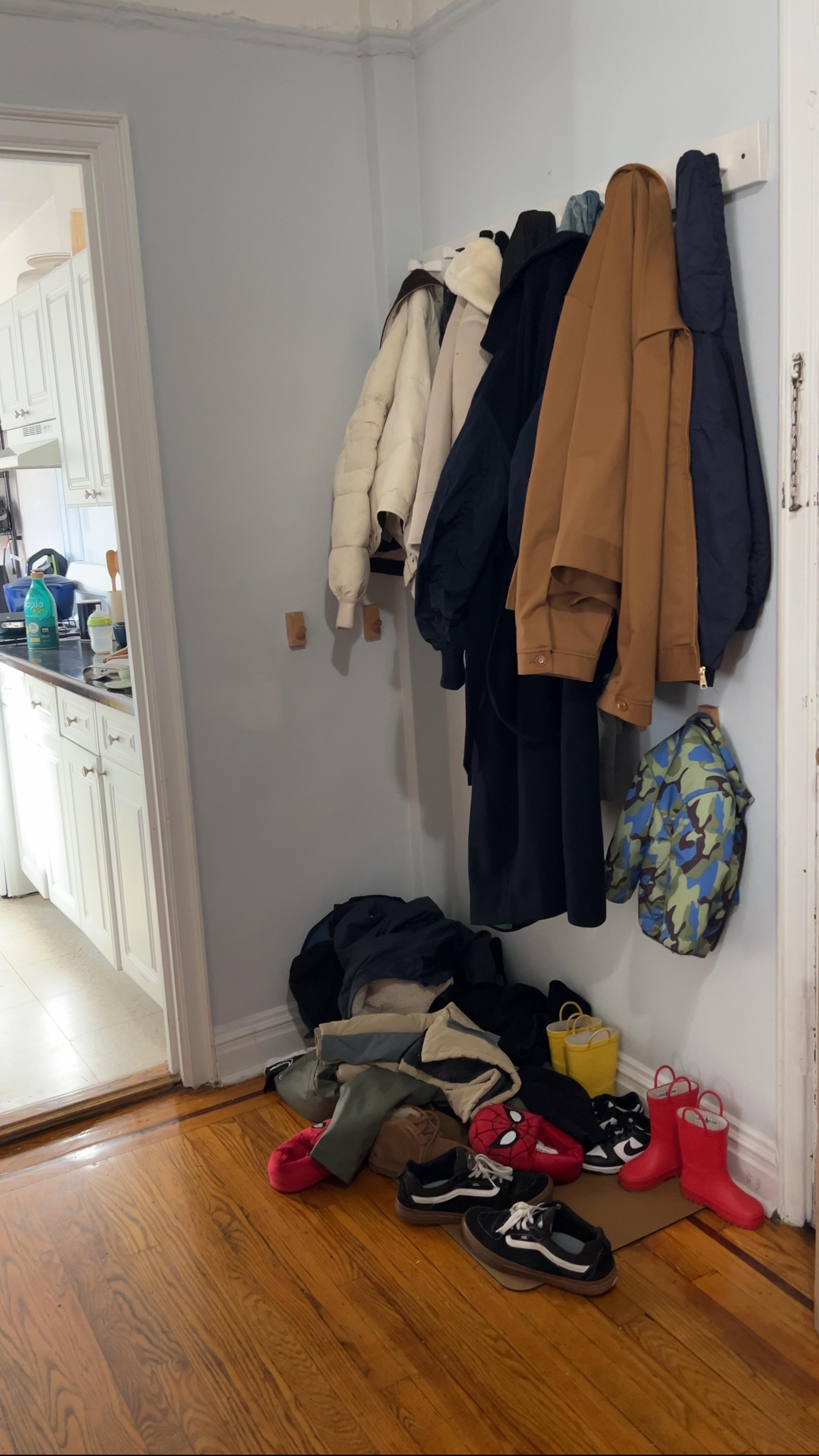 A cluttered entryway with shoes and coats scattered on the floor.