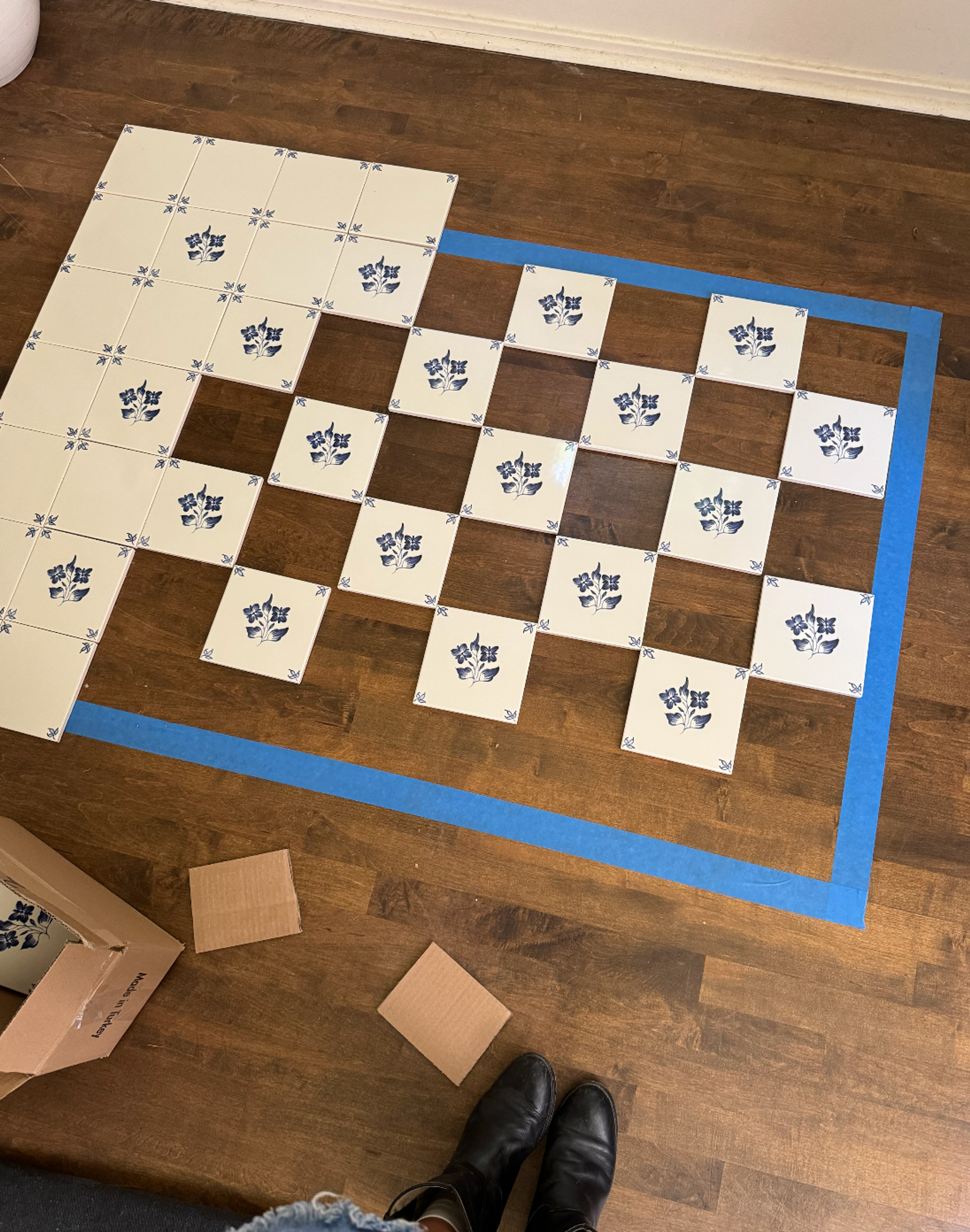 A professional laying down new tile in a kitchen renovation project.