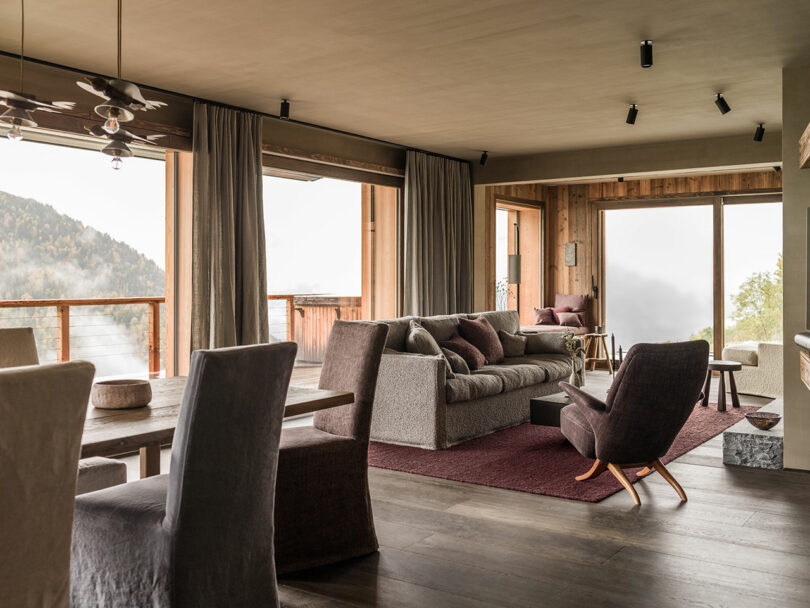 Spacious open-plan living and dining area with large windows overlooking snow-capped mountains.