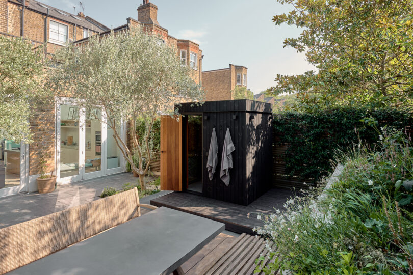 An outdoor garden shower with wooden privacy screens near a house.