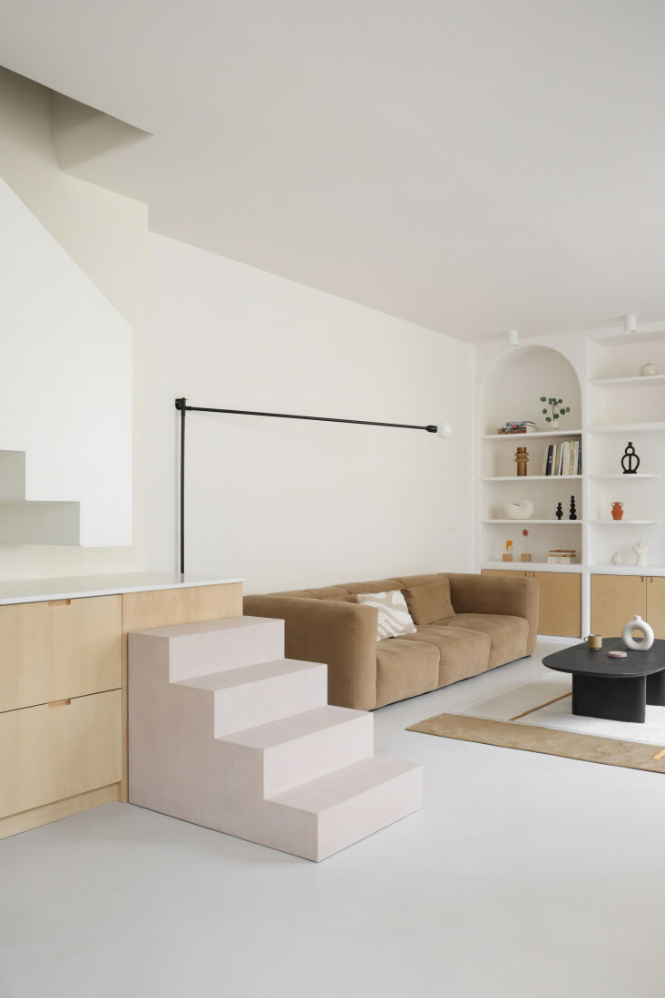 Modern living room with a Hay Mags sofa next to the lower concrete steps of the integrated staircase.