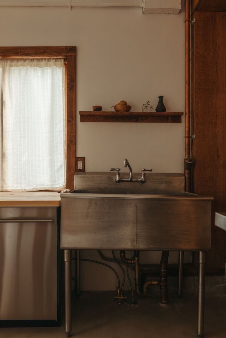 Close-up of an industrial stainless steel sink with exposed copper plumbing.