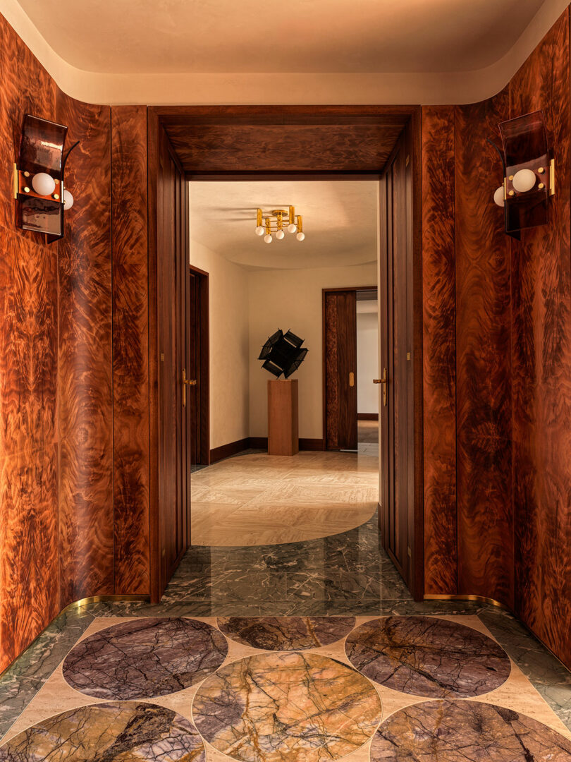 A wood-paneled hallway in the Watergate apartment featuring basketweave travertine flooring and a geometric black sculpture.