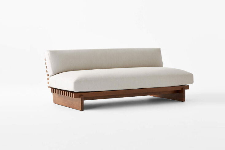 A built-in sofa made of warm-toned red-gum eucalyptus wood with light cushions.