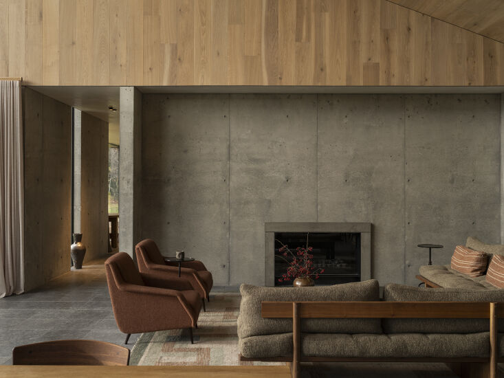 Living room interior featuring limestone floors, oak paneling, and chestnut-colored designer furniture.