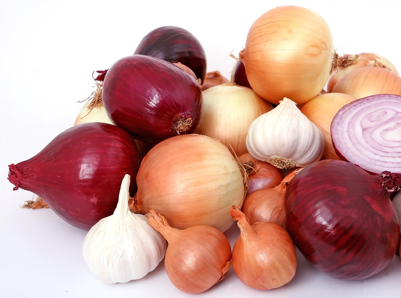 Garlic bulbs and red onions stored in a breathable metal wire basket in a kitchen pantry