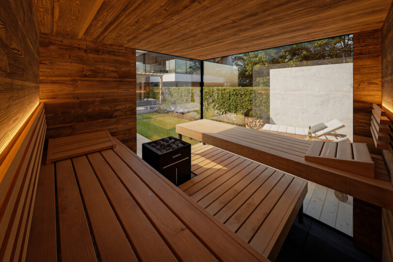 Interior of a modern wooden sauna with clean horizontal lines and large glass windows looking out to a garden.
