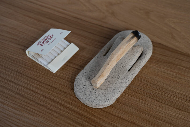 A minimalist setup of matches and a stone holder on a wooden surface.