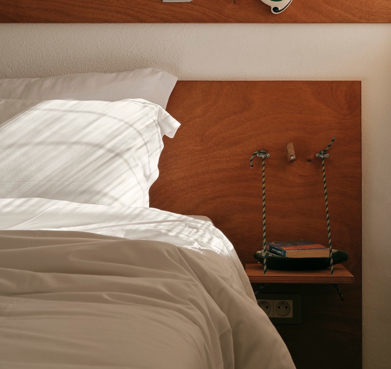 Graphic text overlaying a minimalist bedroom scene reading Small Space DIY Idea: Fold-Down Nightstands.