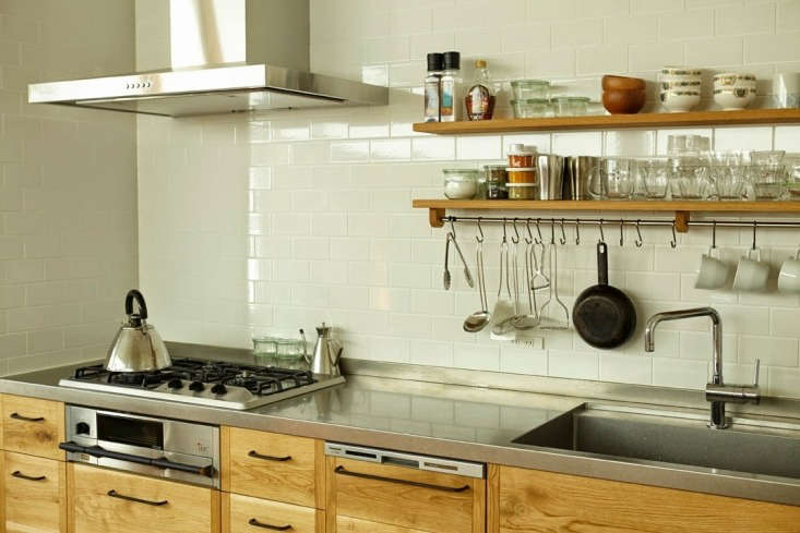 A kitchen interior featuring stainless steel counters and a traditional Japanese fish grill integrated into wood cabinetry.