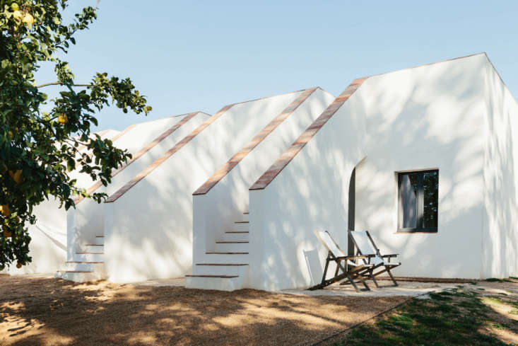 A wide shot showing the two separate minimalist white buildings of the retreat.