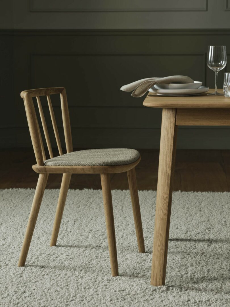 The Éter Chair positioned at a dining table on a textured rug in a softly lit, modern interior.