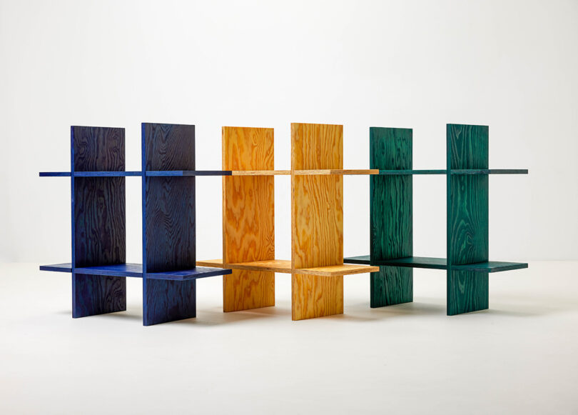 Three freestanding wooden shelving units in blue, yellow, and green.