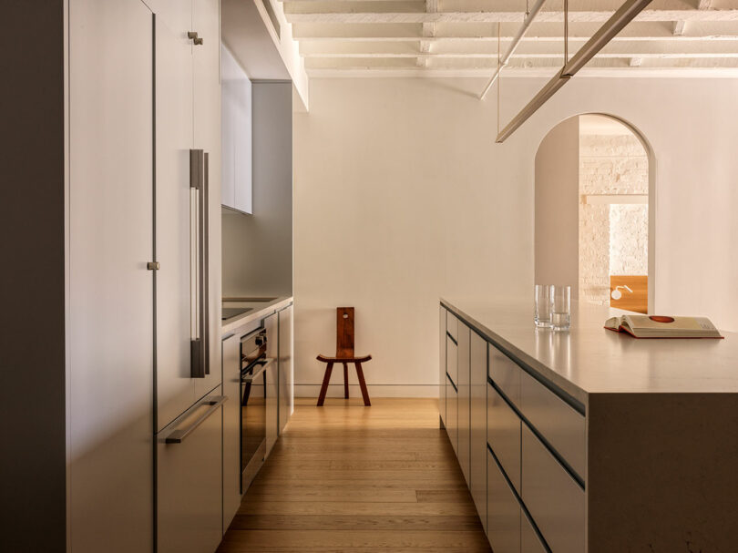 A minimalist kitchen island with white cabinetry and dark wooden flooring.