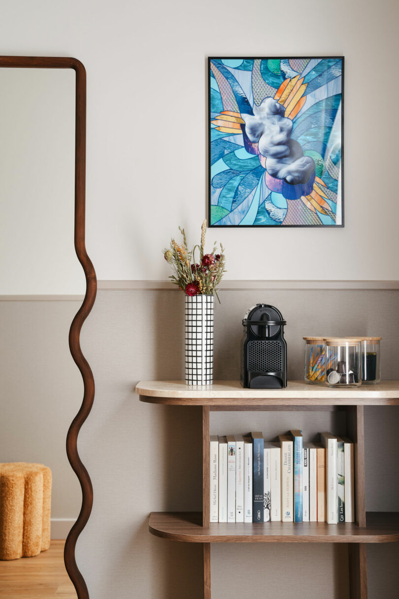 A console table featuring a vase of dried flowers and abstract artwork by François Nugues.
