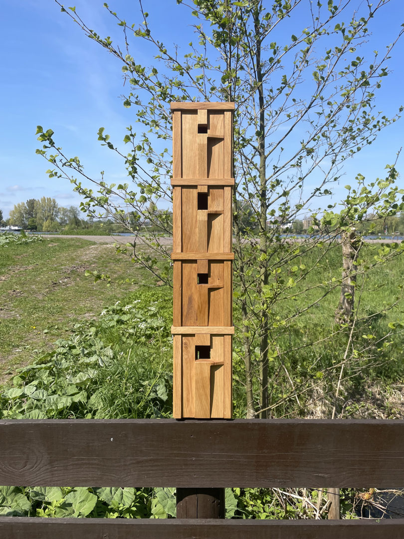 A stack of four handcrafted modern wooden birdhouses outdoors.