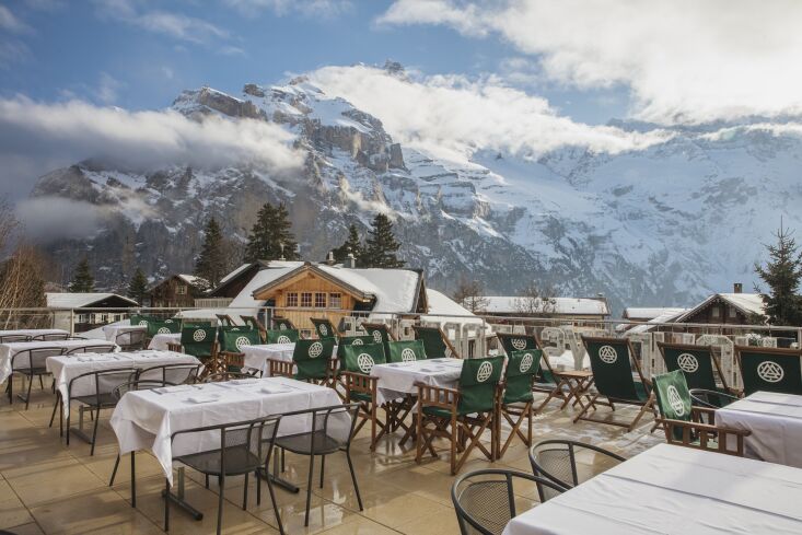 A large outdoor terrace with wooden seating overlooking the alpine landscape.