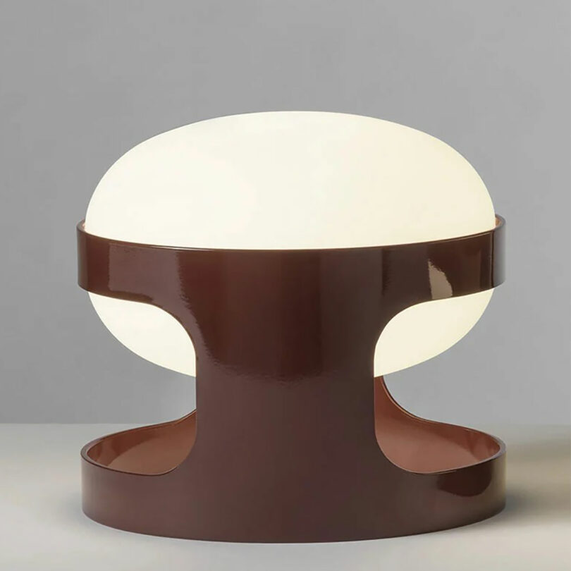 A modern table lamp with a warm white shade and a glossy brown base.