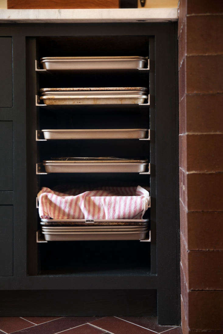 A vertical metal speed rack holding several aluminum baking sheets.